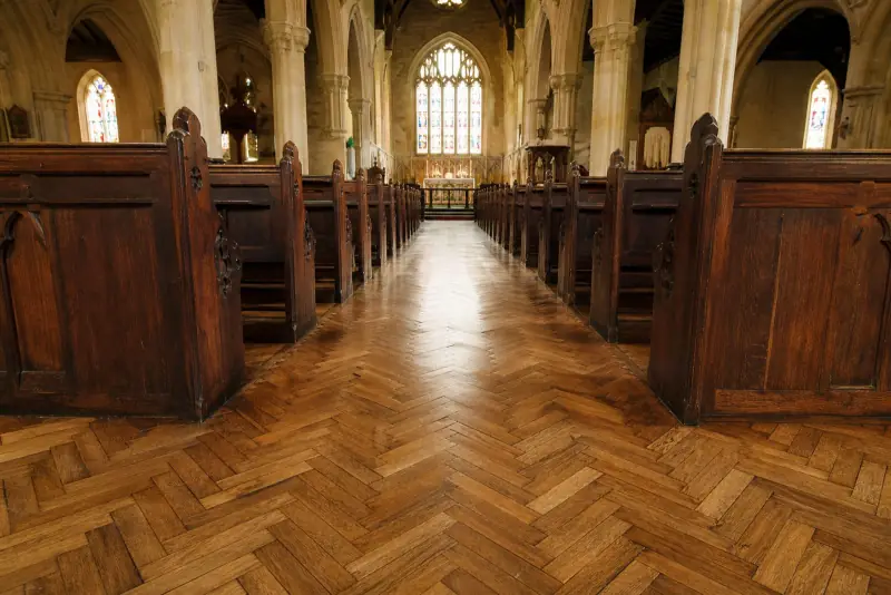 Restored aged-oak herringbone parquet floor down the nave of a traditional church